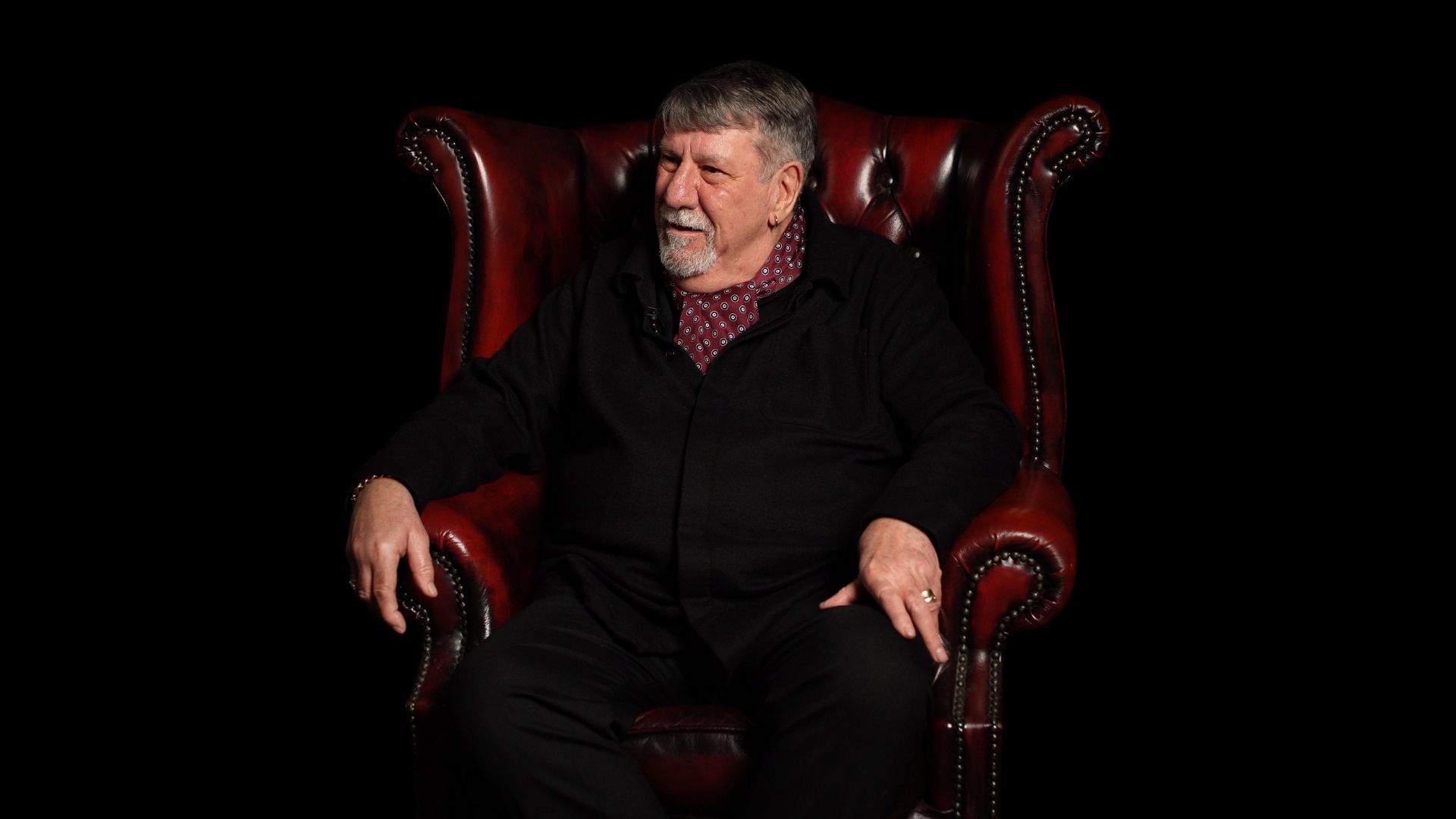 Carl Chinn seated in a red leather chair